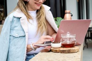 A woman sits outdoors with her laptop, utilizing self-service tools for customer service.